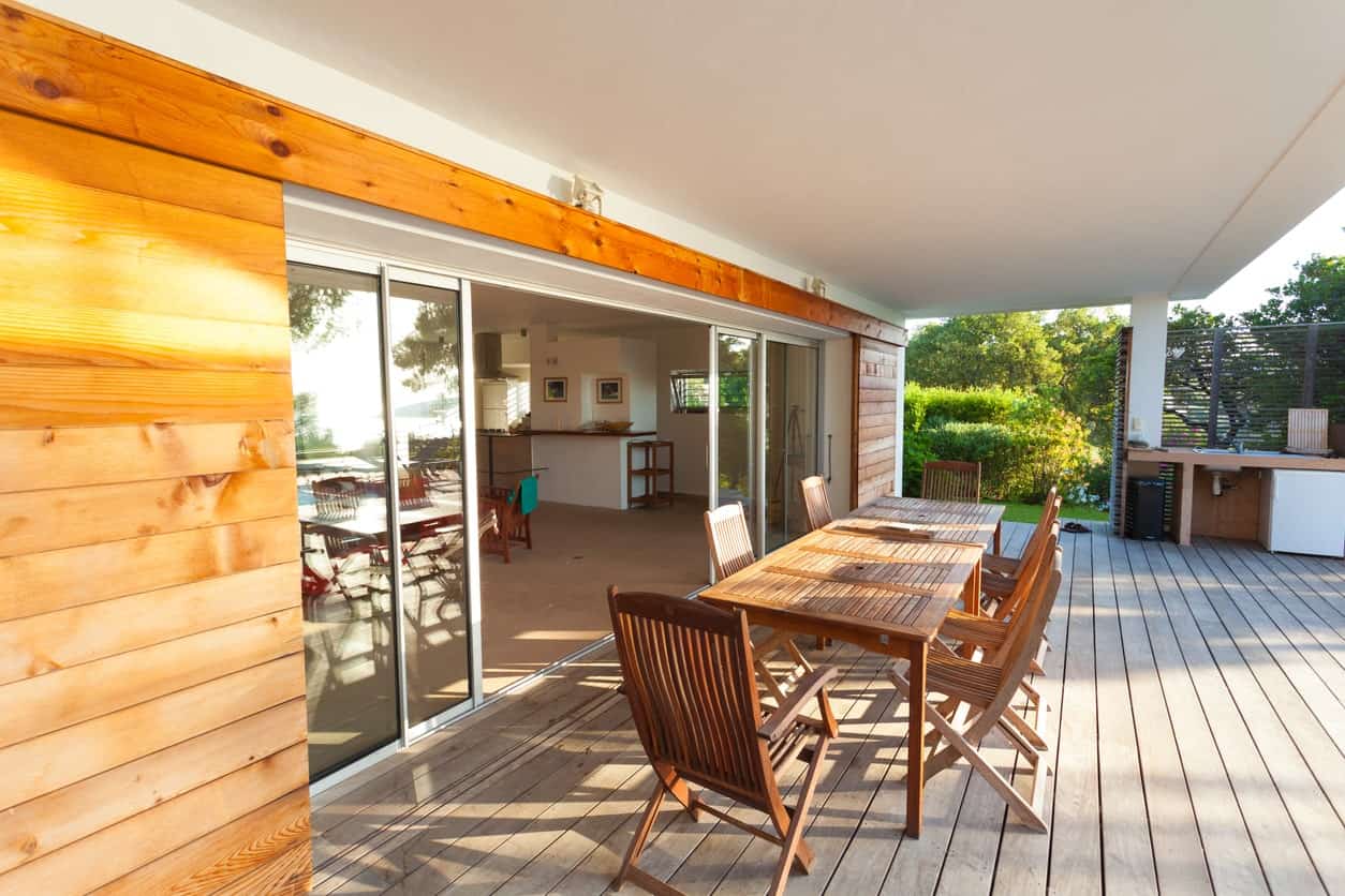 A covered deck offering a large wooden dining table set.