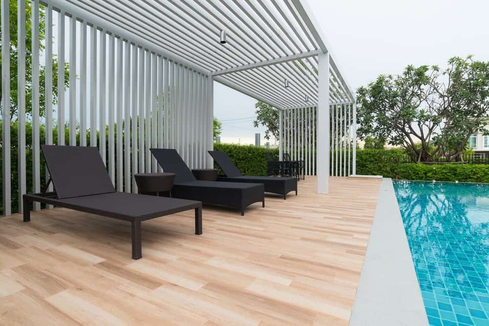 Pool-side deck boasting a set of dark finished rattan lounging seats.