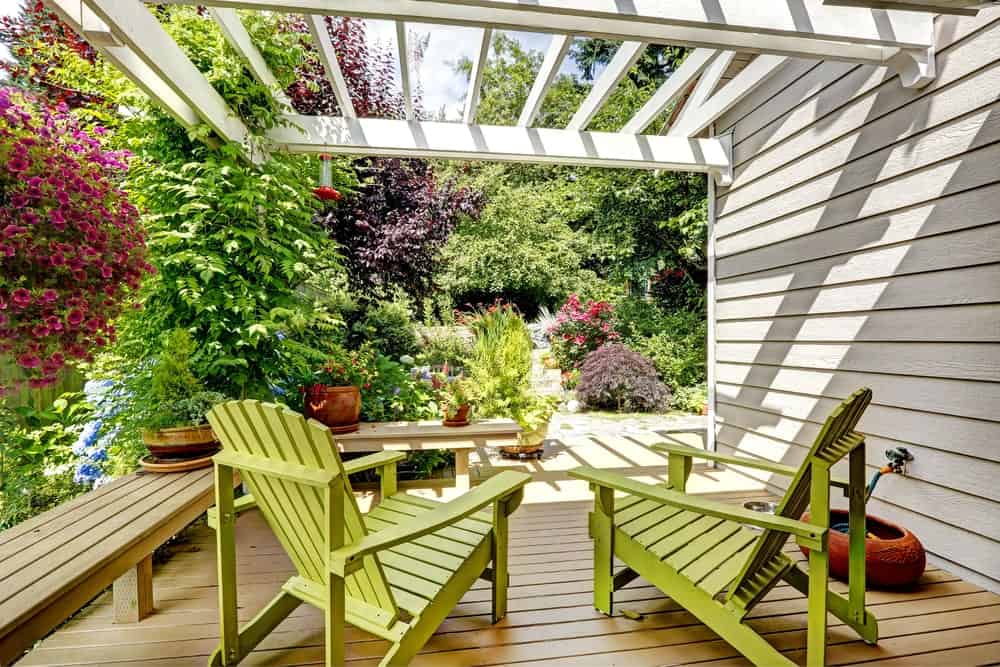 This deck with wooden loungers and bench is surrounded by lovely flowers and greens.