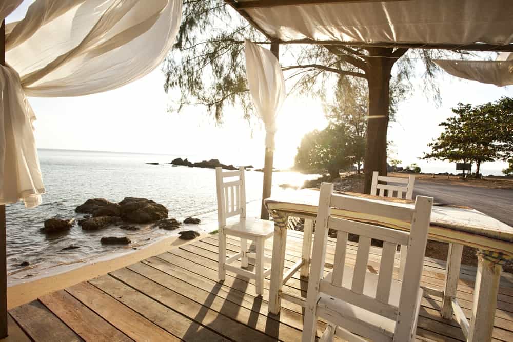 A sea-side deck with a small dining table set overlooking the stunning ocean view.