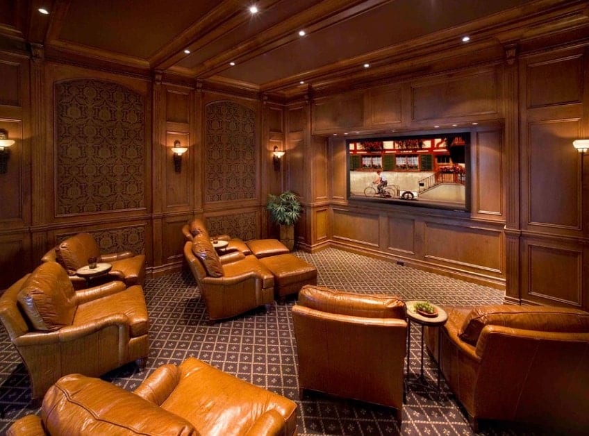 This large home theater features brown walls and ceiling matching the brown leather sectional seats set on the classy carpet flooring.