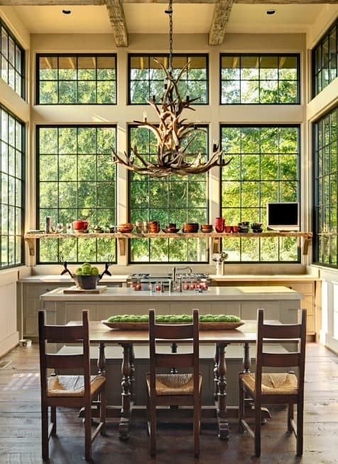 This kitchen features a hardwood flooring and a tall ceiling lighted by a jaw-dropping chandelier.
