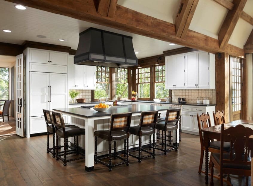 Large kitchen featuring a massive center island with dark finished countertop and bar stools, all set on the hardwood flooring.
