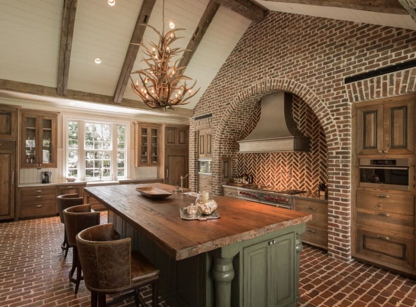 Elegant kitchen featuring tiles flooring and rustic cabinetry. There's a large center island providing space for a breakfast bar lighted by a glamorous chandelier.