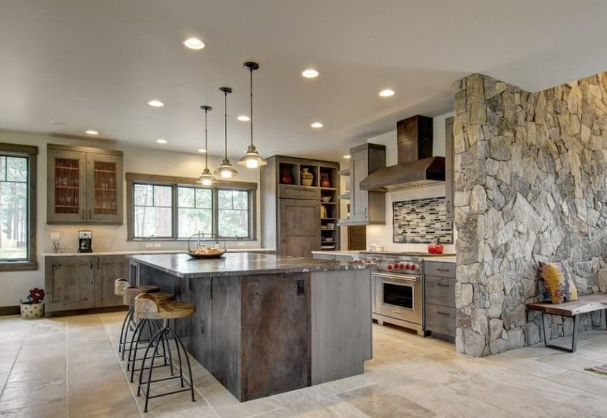 This kitchen boasts rustic cabinetry and center island with a stylish countertop. The whole kitchen is lighted by recessed and pendant lights.