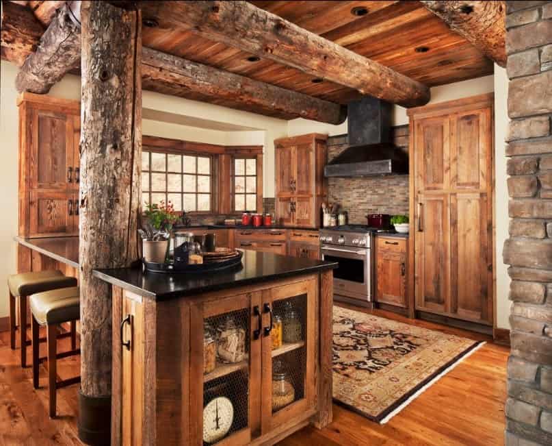 Stunning rustic kitchen with walnut finished cabinetry and counters featuring black countertops. The rug looks very elegant as well.