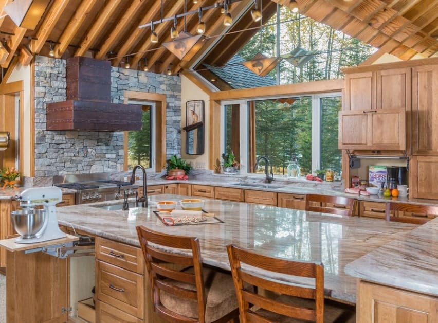 Large rustic kitchen with walnut finished cabinetry and counters along with a massive center island featuring a marble countertop.