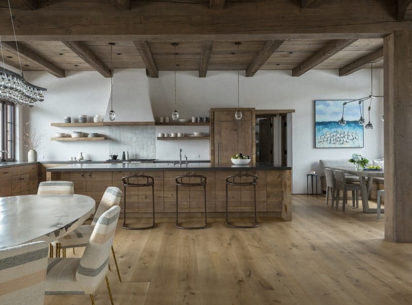 Rustic kitchen with matching hardwood flooring and ceiling lighted by pendant lights. The counters and center island both features smooth dark finished countertops.