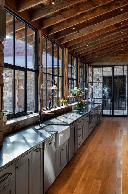 Large rustic kitchen featuring hardwood flooring and stainless steel counters. The ceiling looks stylishly elegant along with its ceiling lights.