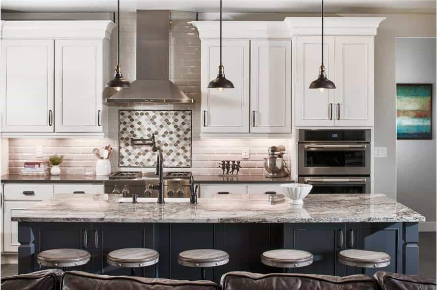 The kitchen includes white cabinetry, stainless steel appliances, and a granite-top island lined with round bar stools.