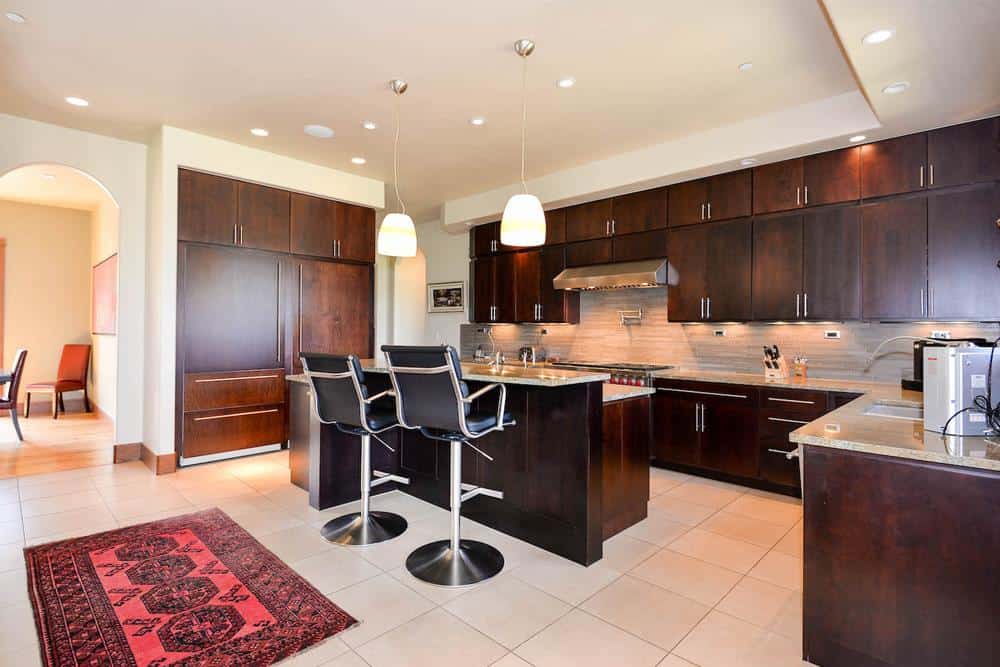 Kitchen with dark wood cabinetry, granite countertops, and a breakfast island with a raised eating bar.
