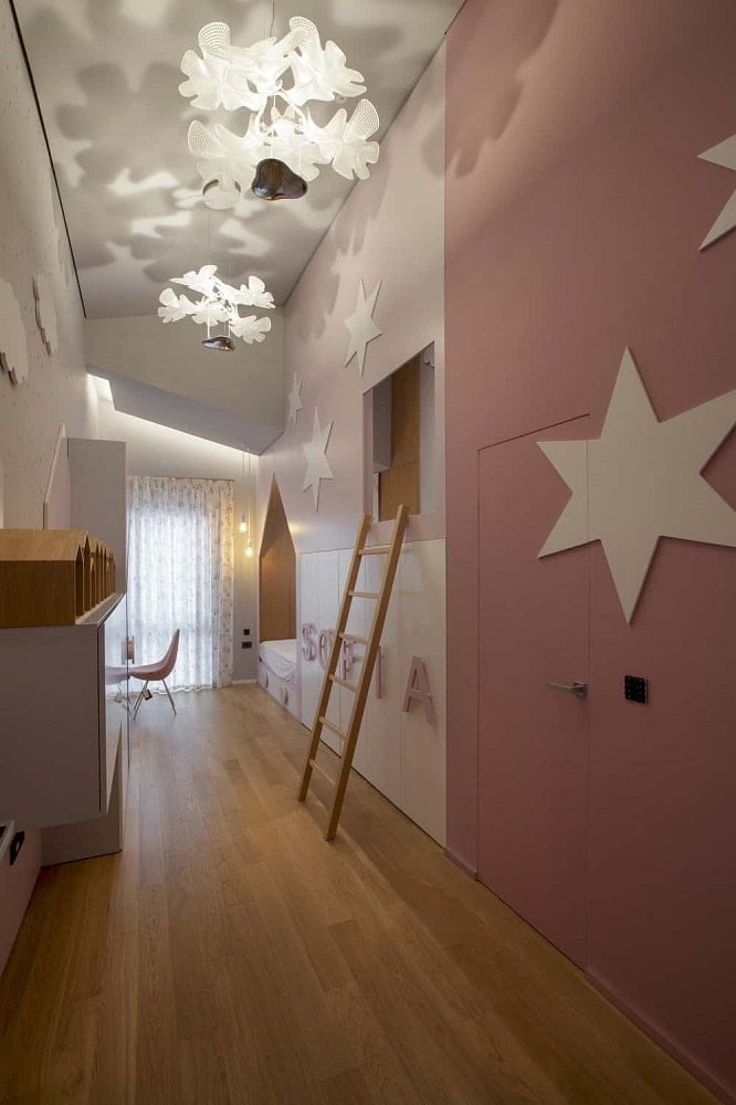 This is a look at the girl's bedroom with a large modern pink structure on one side that has built-in cabinetry that also houses the bed across from the study area.