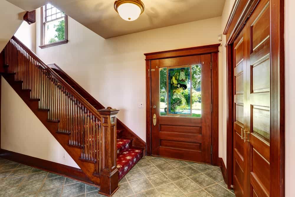 A small home entry with a staircase boasting attractive red carpet floors with hardwood rails.