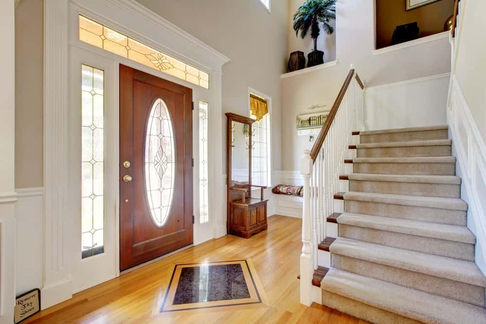A small home entry with a staircase with carpet floors and white railings.