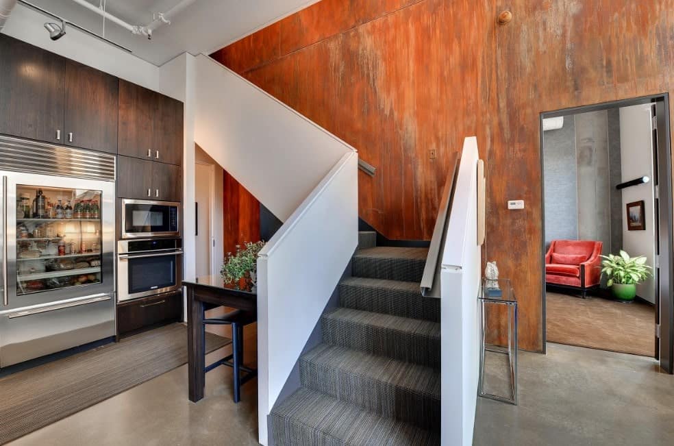 A modish L-shaped staircase with stylish gray carpet floors and steel handrails.
