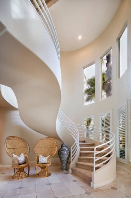This home boasts a stunning staircase with brown carpet floors and white railings.