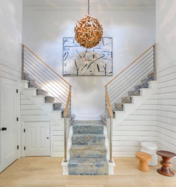 A split staircase with charming carpet floors and steel railings. There's an attractive wall decor on the middle as well.