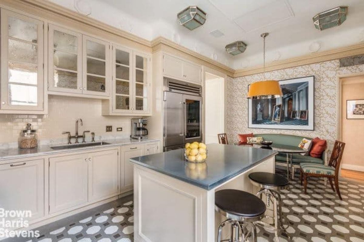 This kitchen boasts classy flooring and ceiling. It also offers a small center island and an elegant dining nook on the side.