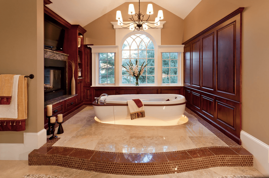 Primary bathroom with an elegant bathtub lighted by a fabulous chandelier set on the room's tall ceiling.