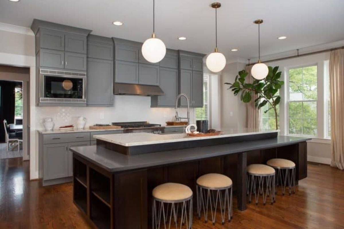 This single wall kitchen provides a large and stunning center island and breakfast bar combo lighted by charming pendant lights.