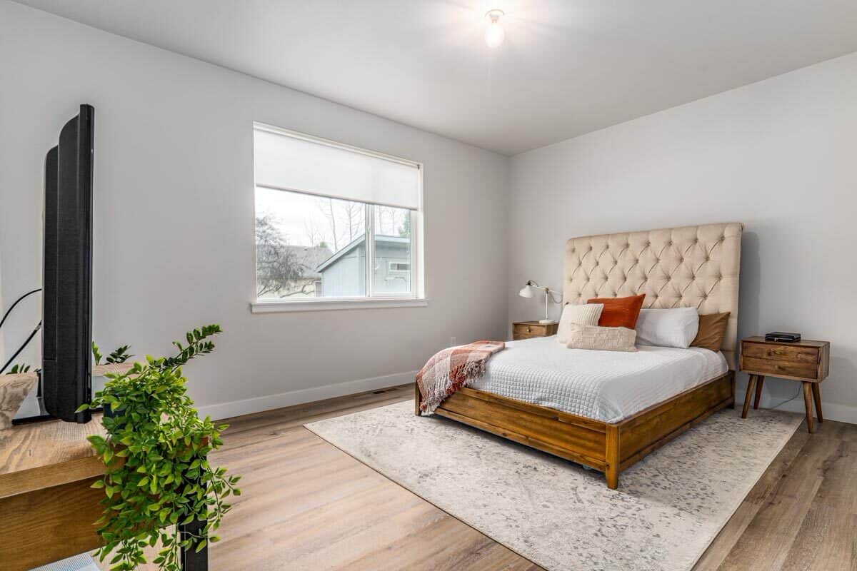 The primary bedroom features a cozy wooden bed with a beige tufted headboard flanked by matching nightstands.