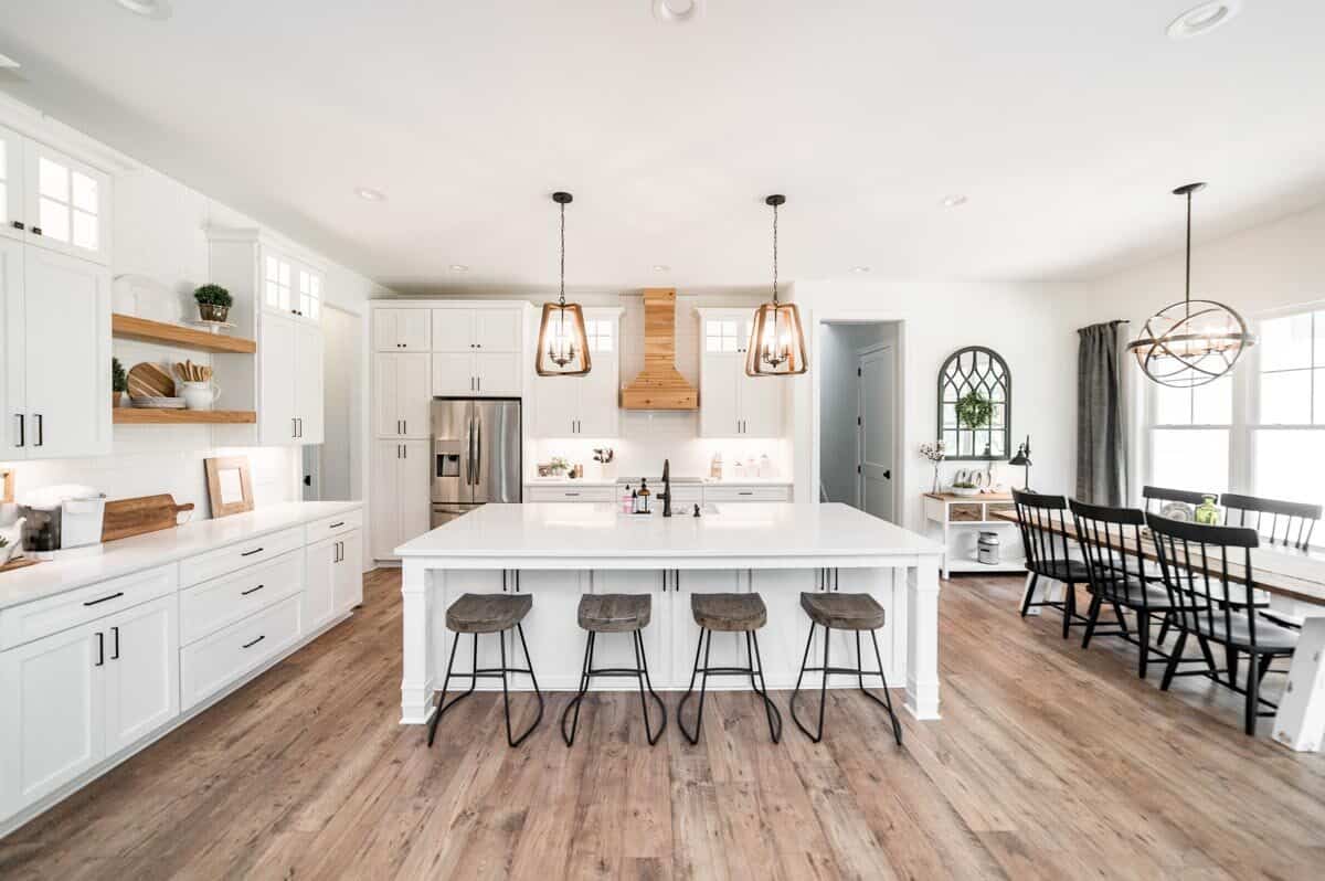 Kitchen with white cabinetry and a matching breakfast island lined with wooden bar stools.