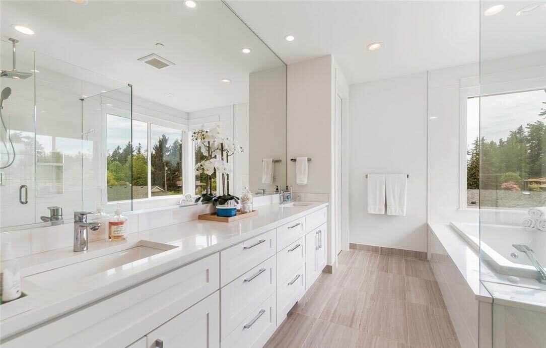 The primary bathroom features a large, white vanity with double sinks and a frameless rectangular mirror.