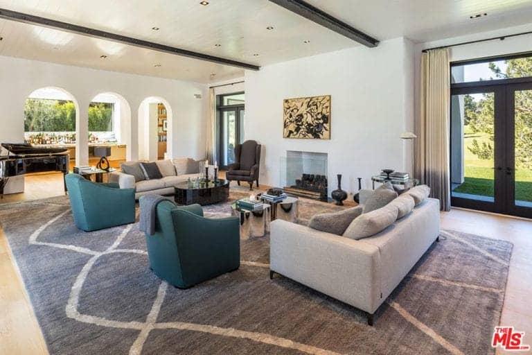 Spacious living room features face to face gray sofas with blue green armchairs and coffee tables on a gray rug.