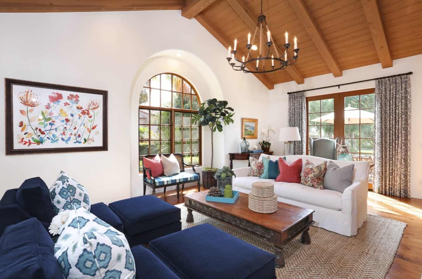 A pair of navy blue fabric chairs with matching ottomans face the wooden center table and white sofa in this white living room.