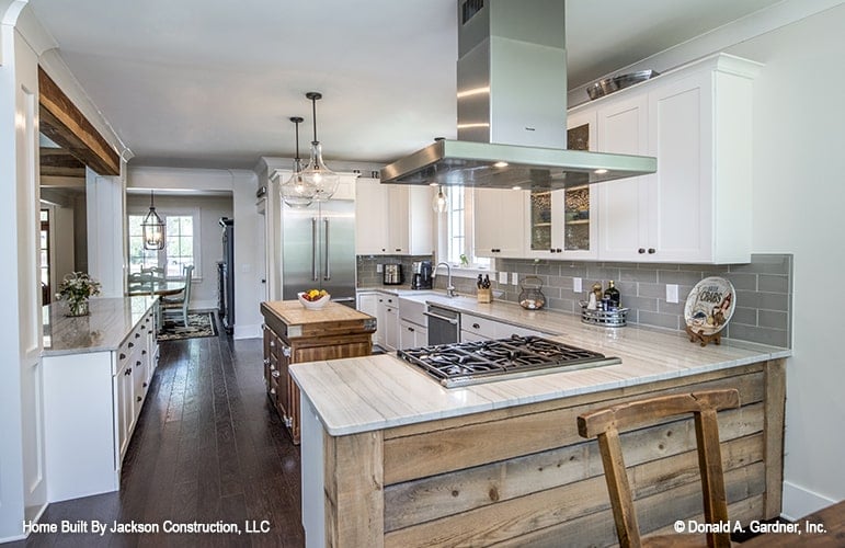 This is a close look at the kitchen that has an L-shaped peninsula paired with a small wooden kitchen island that matches the hardwood flooring.