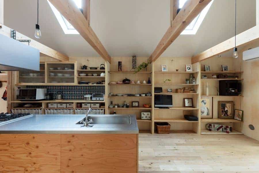 This is a close look at the kitchen that has large wooden kitchen island across from the built-in wooden shelves that are used for storage and counter space.