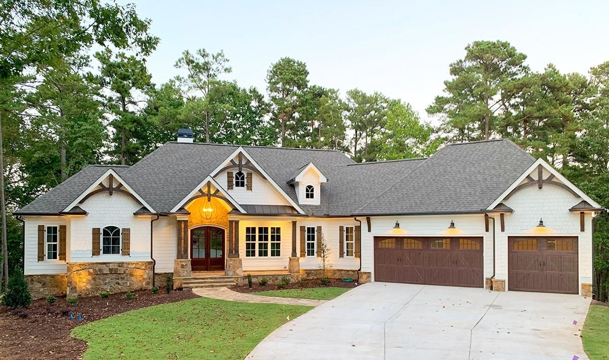 This craftsman-style home features decorative trims and stone accents that complement well with the lush green lawn and concrete driveway.