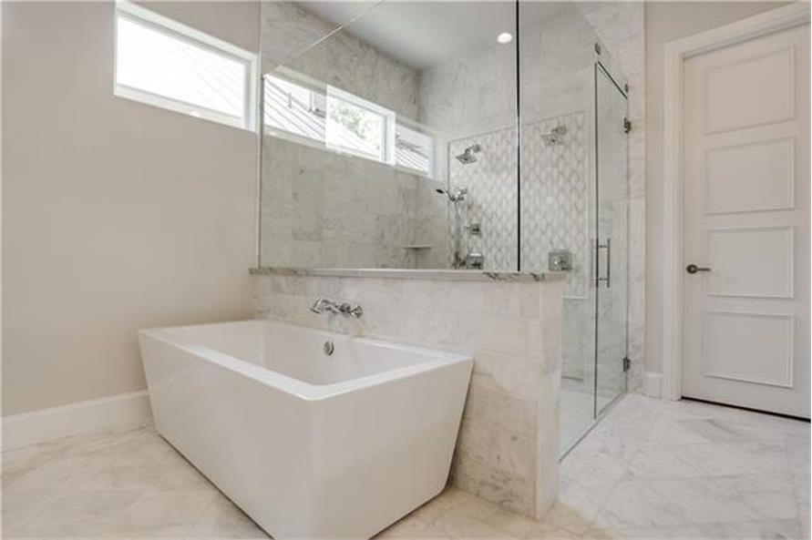 The primary bathroom includes a freestanding tub and a walk-in shower brightened by clerestory windows.