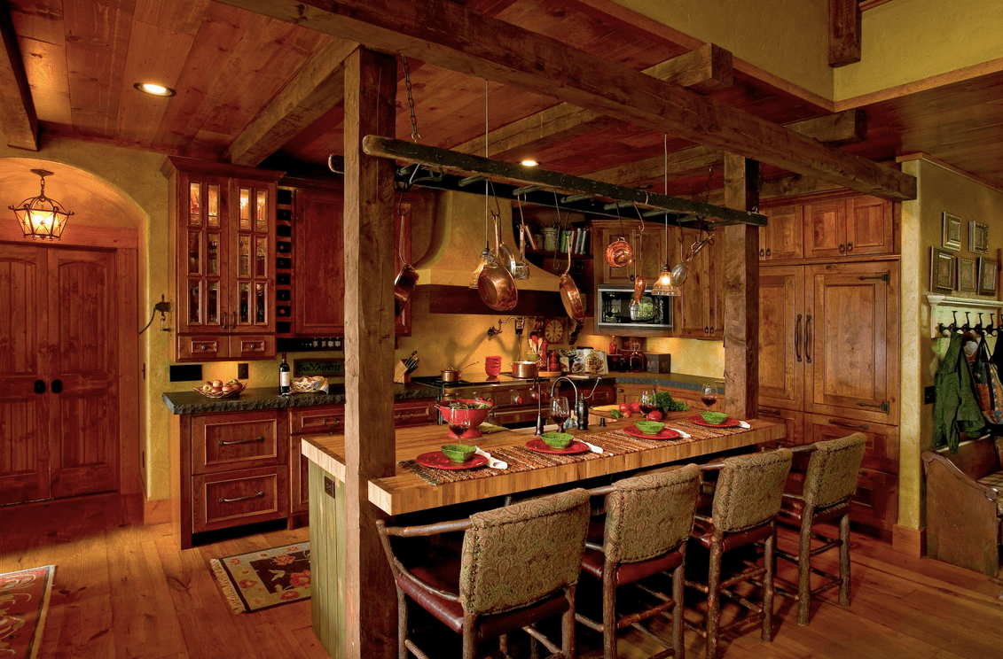 Cozy kitchen showcases wooden cabinetry and a breakfast island lined with wood beams and pot rack that resembles a ladder.