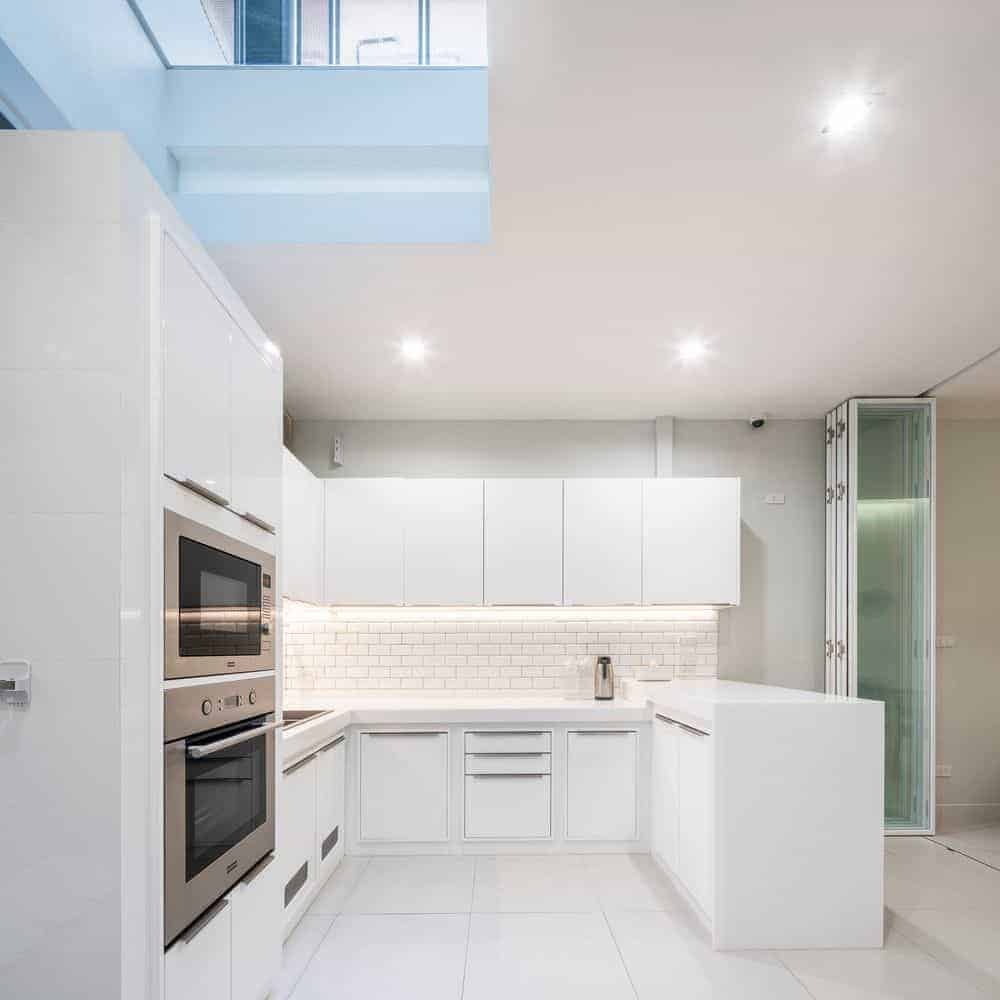 This is a close look at the kitchen that has bright white cabinetry to its U-shaped peninsula that makes the stainless steel appliances stand out. These are then complemented by the white subway tiles.