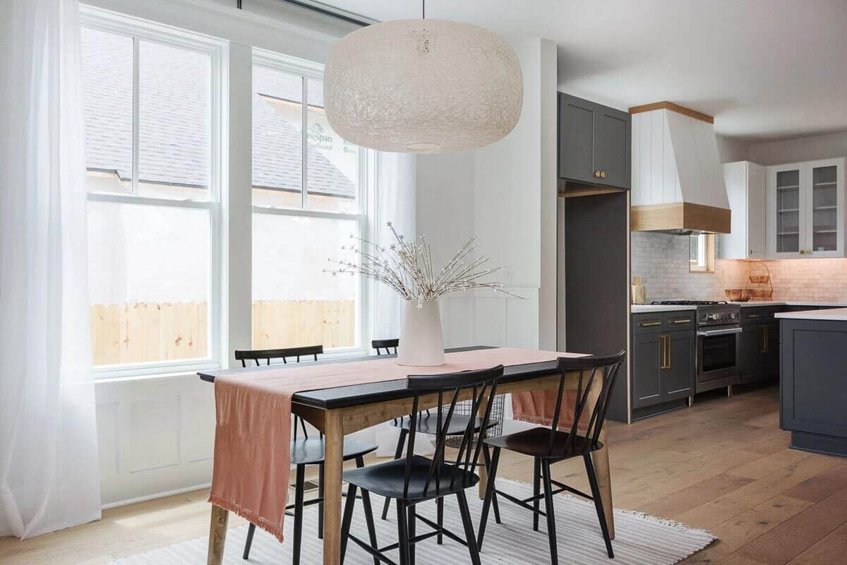 The dining area has a two-tone wooden dining set and an oversized pendant light.