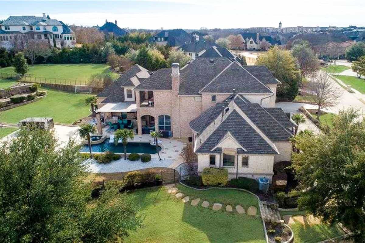 This is an aerial view of the back of the house that shows the backyard pool along with a stone slab walkway going through the grass lawn.