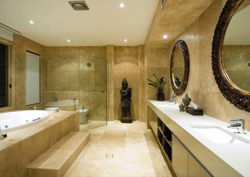 Asian-style primary bathroom boasting an eye-catching statue on the side. The room offers a single sink counter with two sinks along with a drop-in tub and a walk-in shower room.