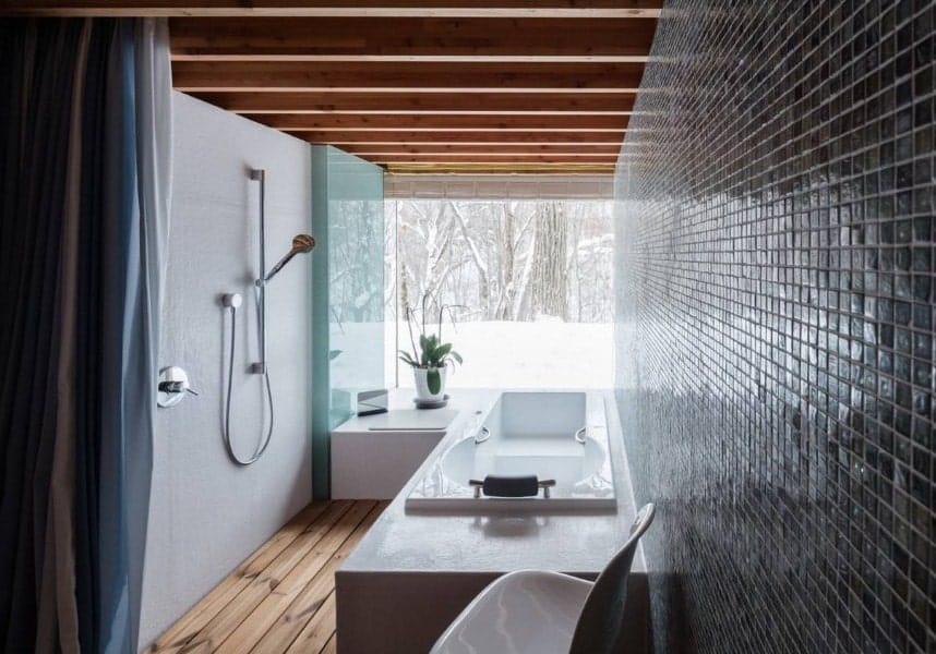 A small Asian-style bathroom featuring a drop-in tub and an open shower. The room has a ceiling with beams along with hardwood flooring.