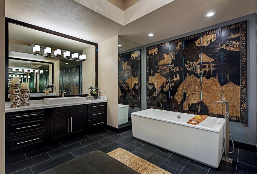 Asian-style primary bathroom with a very artistic large wall decor along with stylish tiles flooring. The room offers a freestanding tub along with a single sink counter with a large vessel sink.