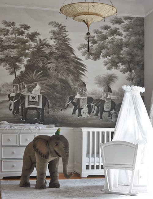 Elephant themed nursery with a unique chandelier and white cabinet complementing with the crib and rocking bassinet that's covered in a round canopy.