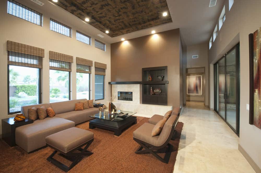 Large formal living space with a brown sofa set and a stylish tray ceiling. The room also offers a fireplace and a brown area rug.