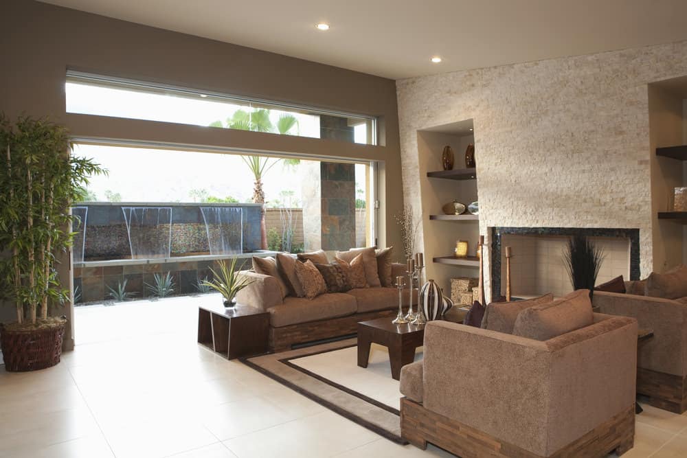 A spacious formal living room featuring a brown sofa set and a stylish area rug. The room offers a large fireplace and built-in shelves.