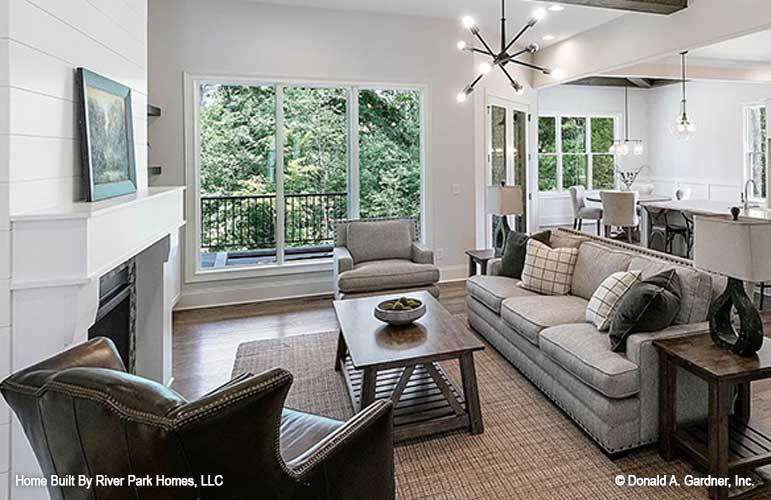 The living room has a gray sofa with matching cushioned arm chairs and a wooden coffee table across from the fireplace with a white mantle.