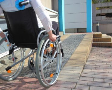 Woman in a wheelchair going up a ramp to a house