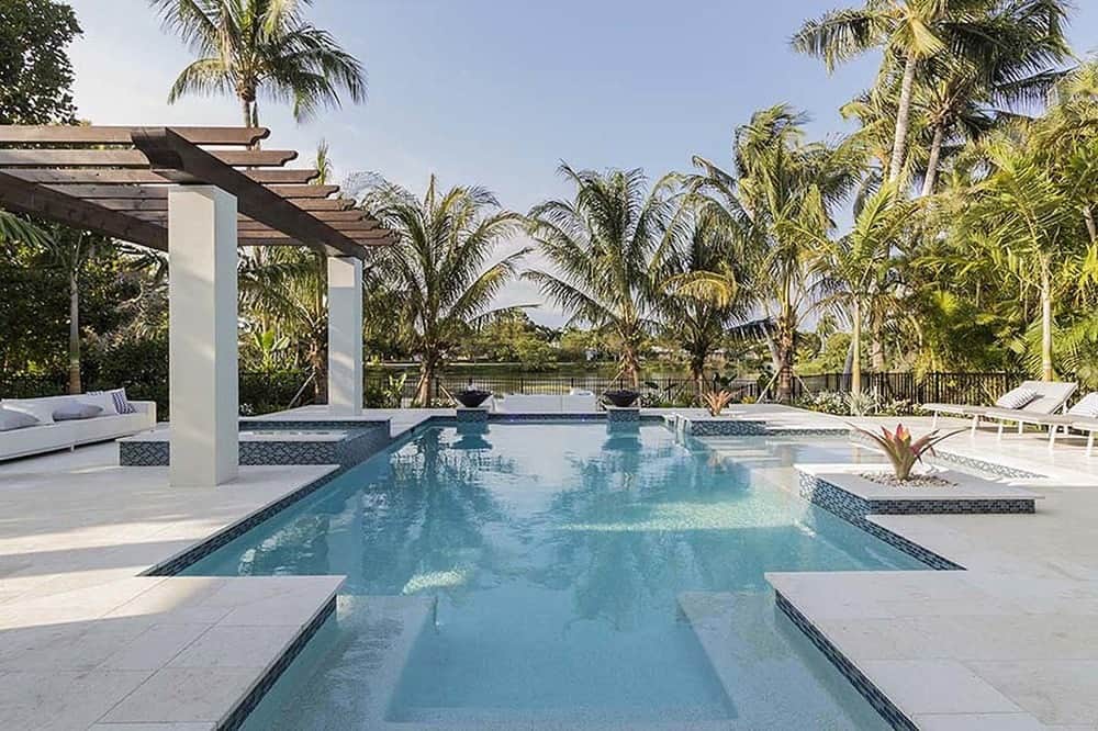 trees This is the back of the house that is dominated by the gorgeous pool with a cabana on the side topped with trellises. The whole backyard is surrounded by tall tropical <a class=