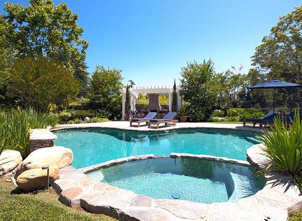This home has an outdoor area with a beautiful garden and has a swimming pool with multiple sitting lounges.