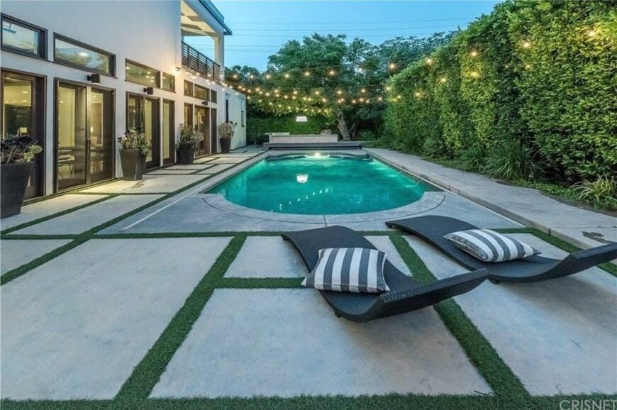 A modern house with a modern outdoor area featuring a stylish walkway and lounging seats. The swimming pool looks very attractive as well.