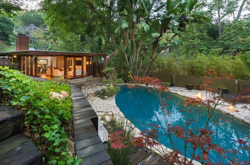 This outdoor area boasts a beautiful garden with healthy plants and trees, along with an enchanting swimming pool.