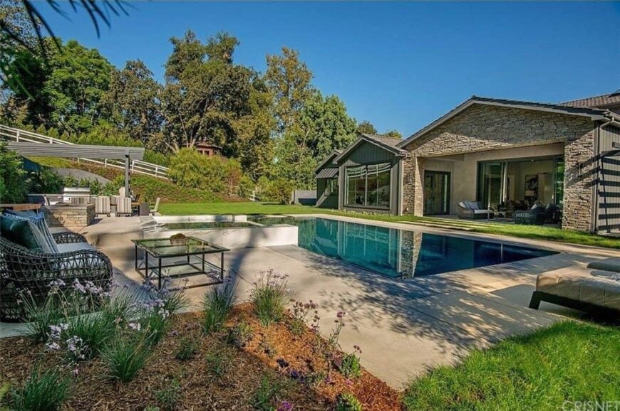 This home offers a gorgeous backyard with a swimming pool, a patio area and an outdoor dining and kitchen.